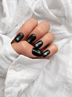 Black Cat Eye press-on nails seen from above on a curled hand against a white shirt cuff