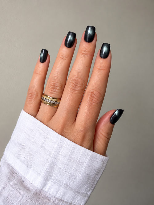 Black Cat Eye press-on nails on a raised hand against a soft grey background